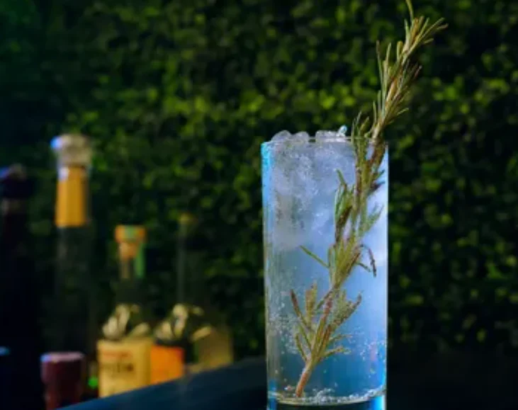Blue cocktail with a rosemary garnish