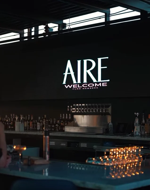 The illuminated AIRE welcome sign above the bar